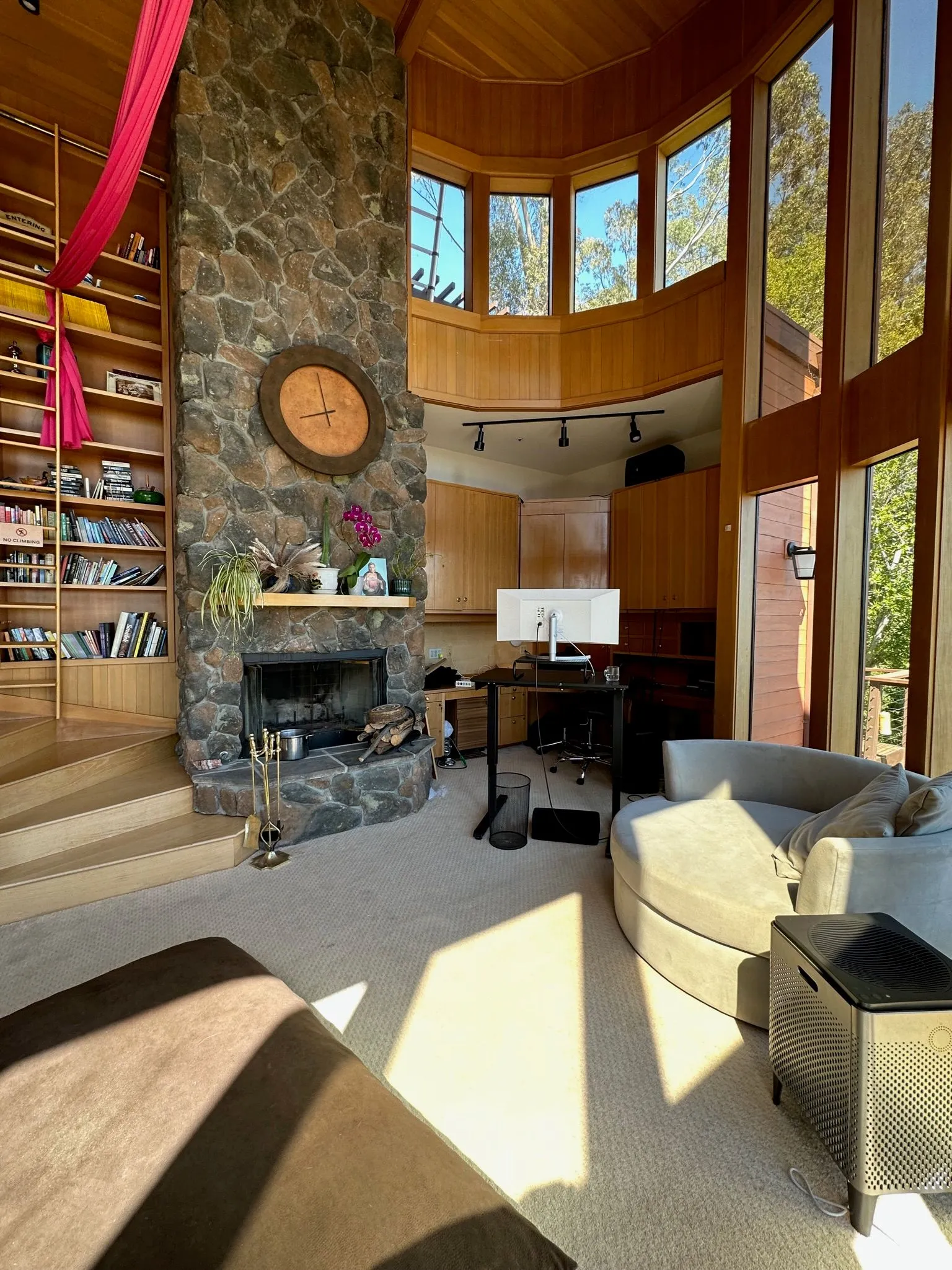A double-height library with a stone fireplace, tall bookshelves, and hanging aerial silks