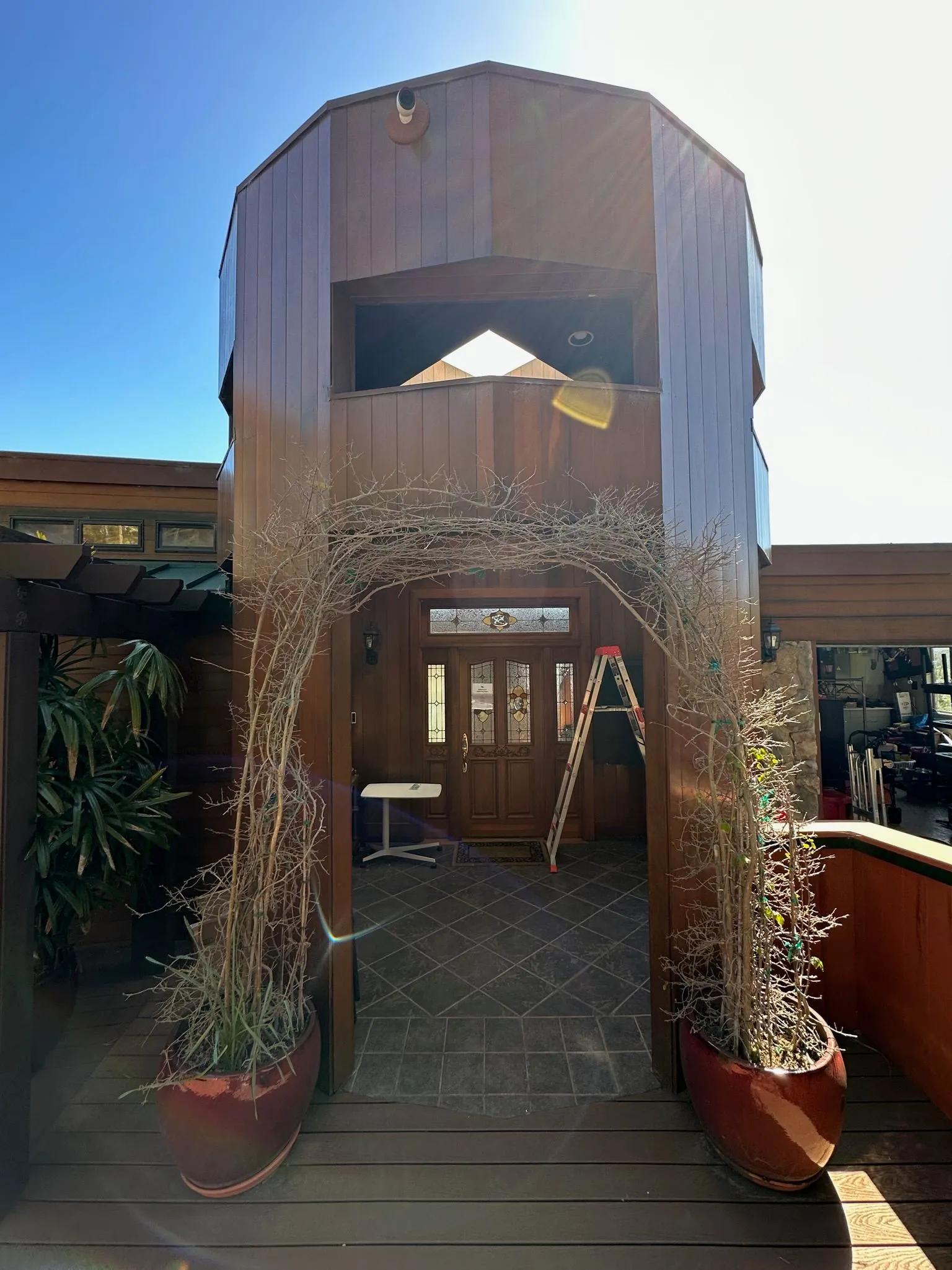 An octagonal cedar entry tower with a stained-glass front door and an arched trellis