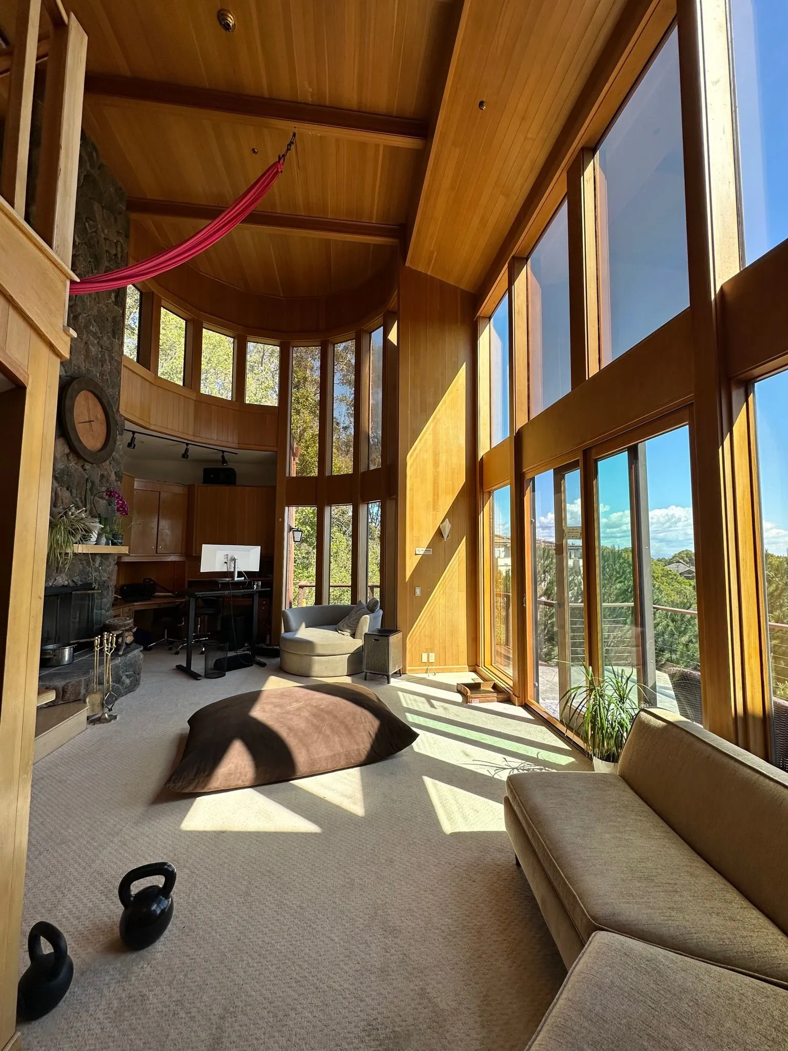 The great room under a vaulted fir ceiling with red aerial silks and a stone fireplace