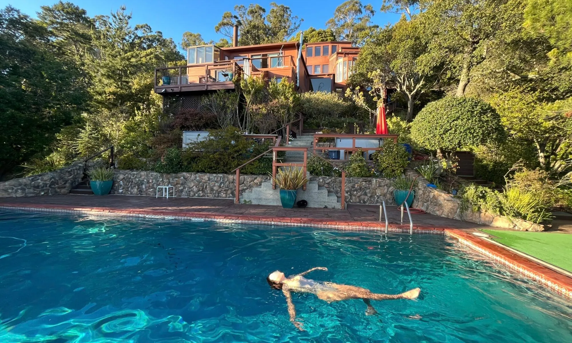 The cedar-clad estate rising in tiers above its saltwater pool on a wooded hillside