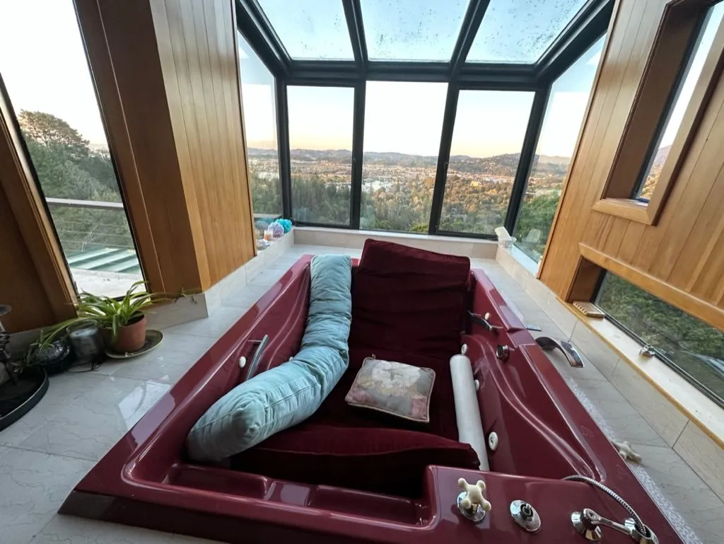 A deep tub in a glass-walled alcove with a panoramic view of the valley